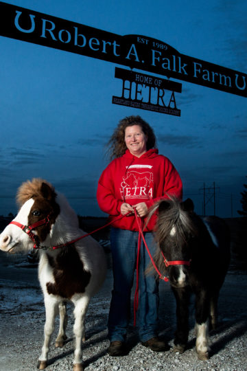 woman under farm sign with ponies