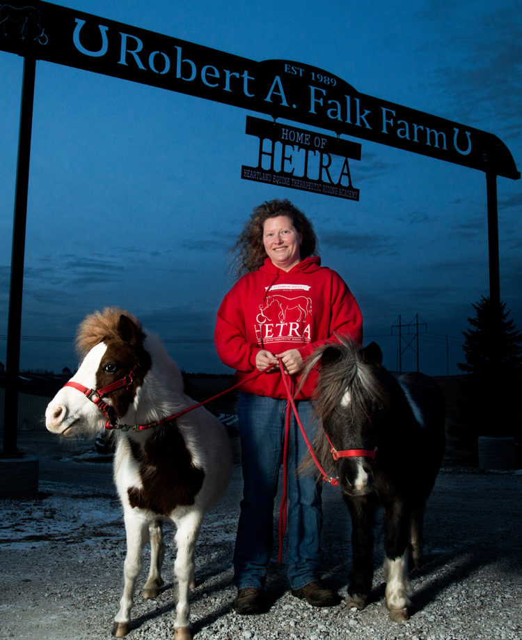 woman under farm sign with ponies