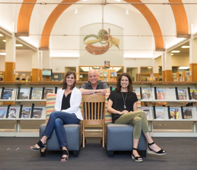 two women and a man at the library