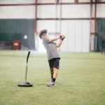 boy hitting a ball off of a tee