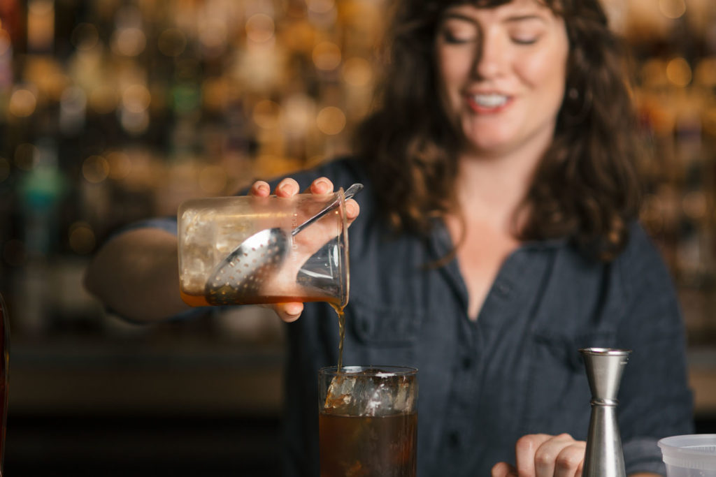 women bartender pouring cocktail
