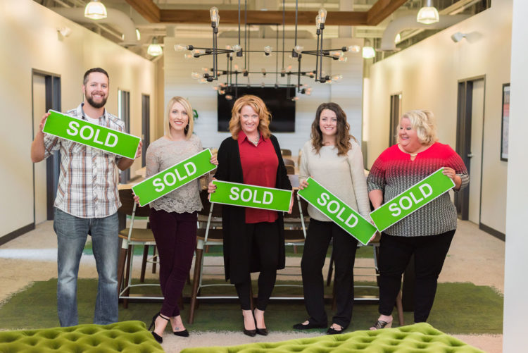 Better Homes staff holding sold signs
