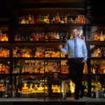 man with shelves of liquor at bar