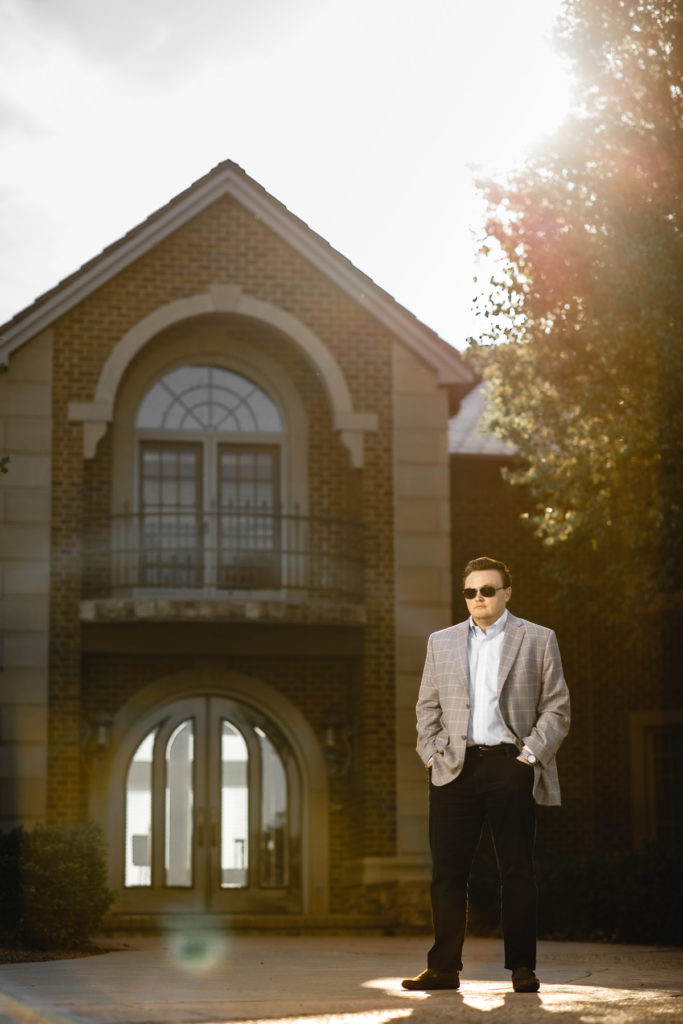 man in suit in front of house